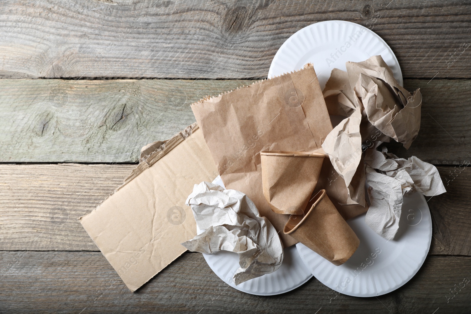 Photo of Different waste paper on wooden table, flat lay. Space for text