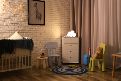Photo of Modern baby room interior with white chest of drawers in evening