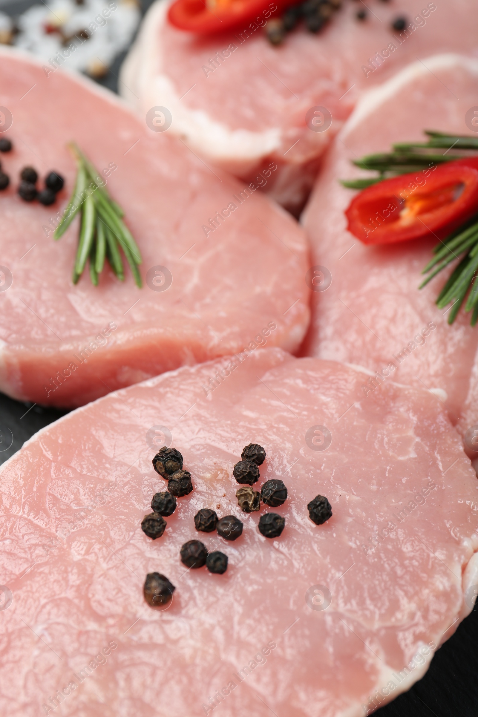 Photo of Pieces of raw pork meat, chili pepper and spices on board, closeup