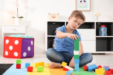 Little autistic boy playing with cubes at home