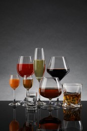 Glasses with different alcoholic drinks on table against gray background