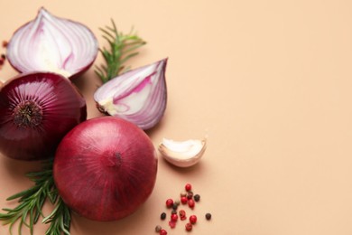 Photo of Fresh red onions, garlic, rosemary and spices on beige background, flat lay. Space for text