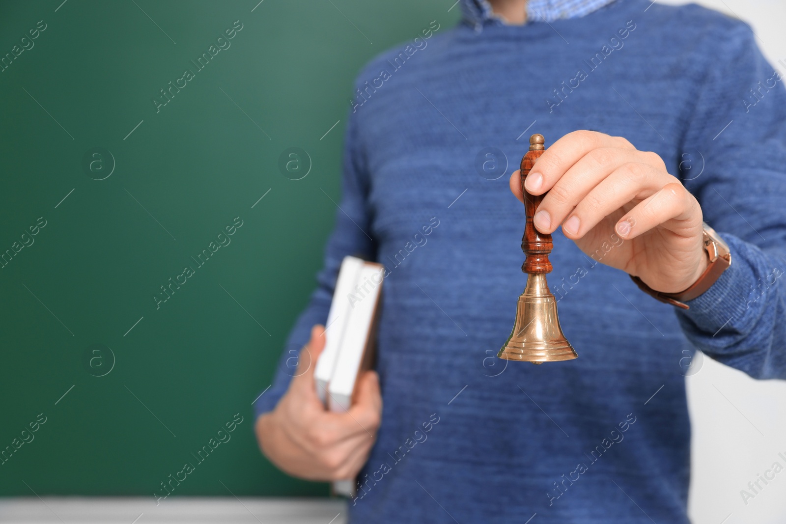 Photo of Teacher with school bell near chalkboard, closeup. Space for text