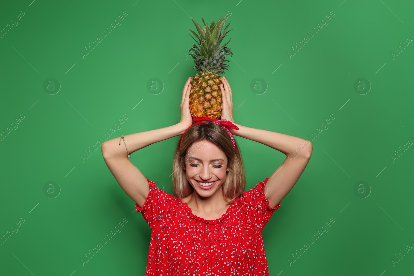 Photo of Young woman with fresh pineapple on green background. Exotic fruit