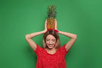 Young woman with fresh pineapple on green background. Exotic fruit