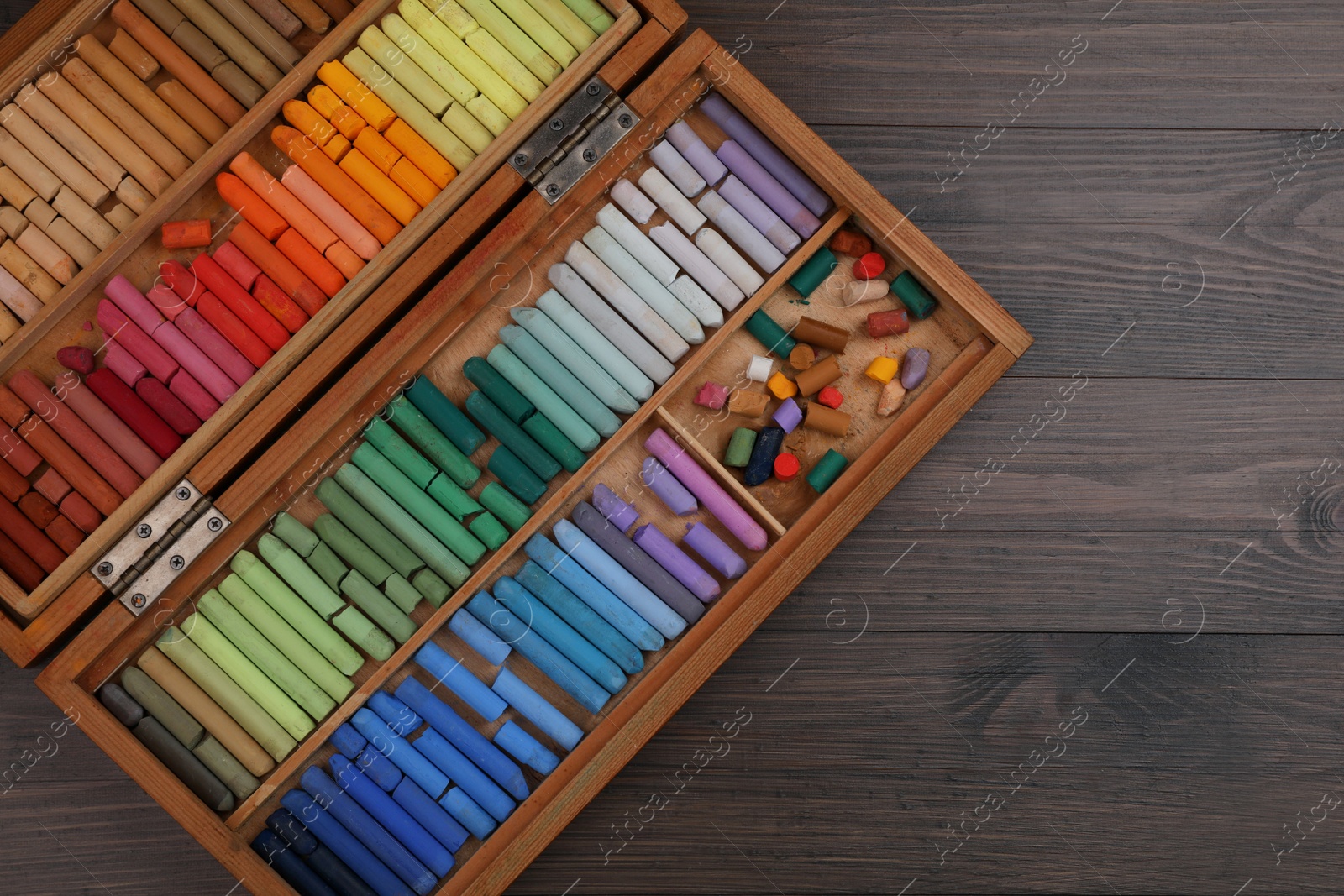 Photo of Drawing pastel set in box on wooden background, top view