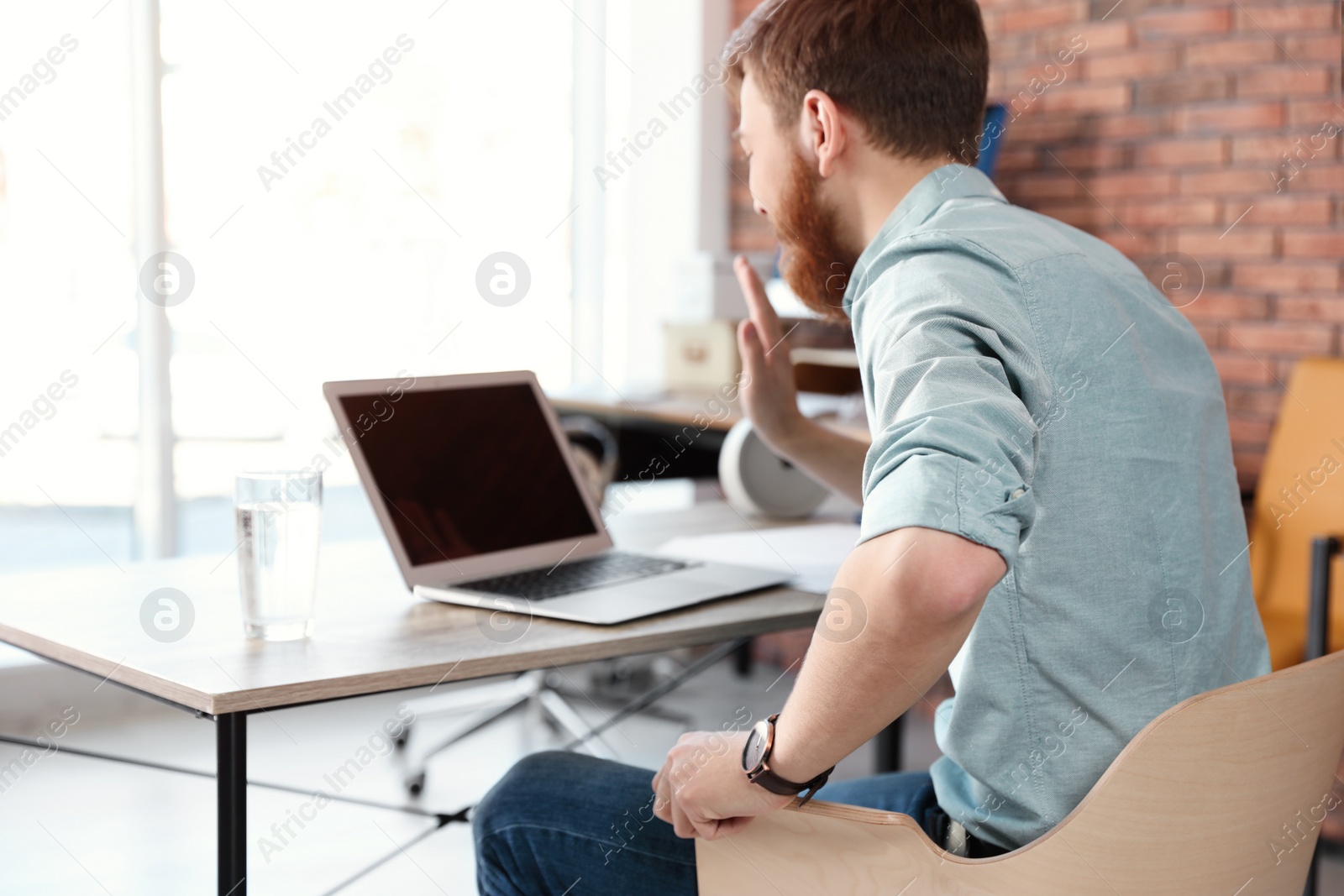 Photo of Young man using video chat on laptop in home office. Space for text