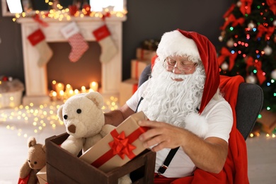 Photo of Authentic Santa Claus holding wooden crate with gifts indoors