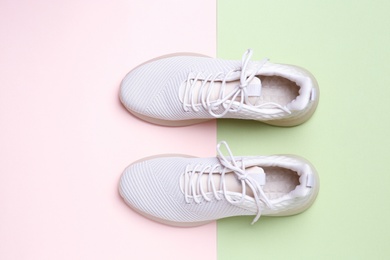 Stylish sporty sneakers on color background, top view