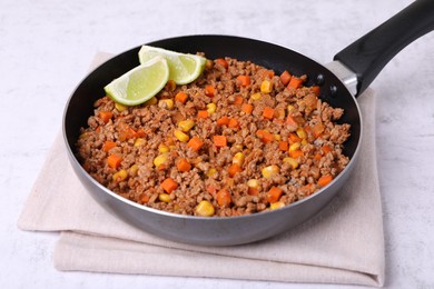 Photo of Fried minced meat, carrot, corn and lime in pan on white textured table