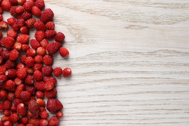 Photo of Many fresh wild strawberries on white wooden table, flat lay. Space for text