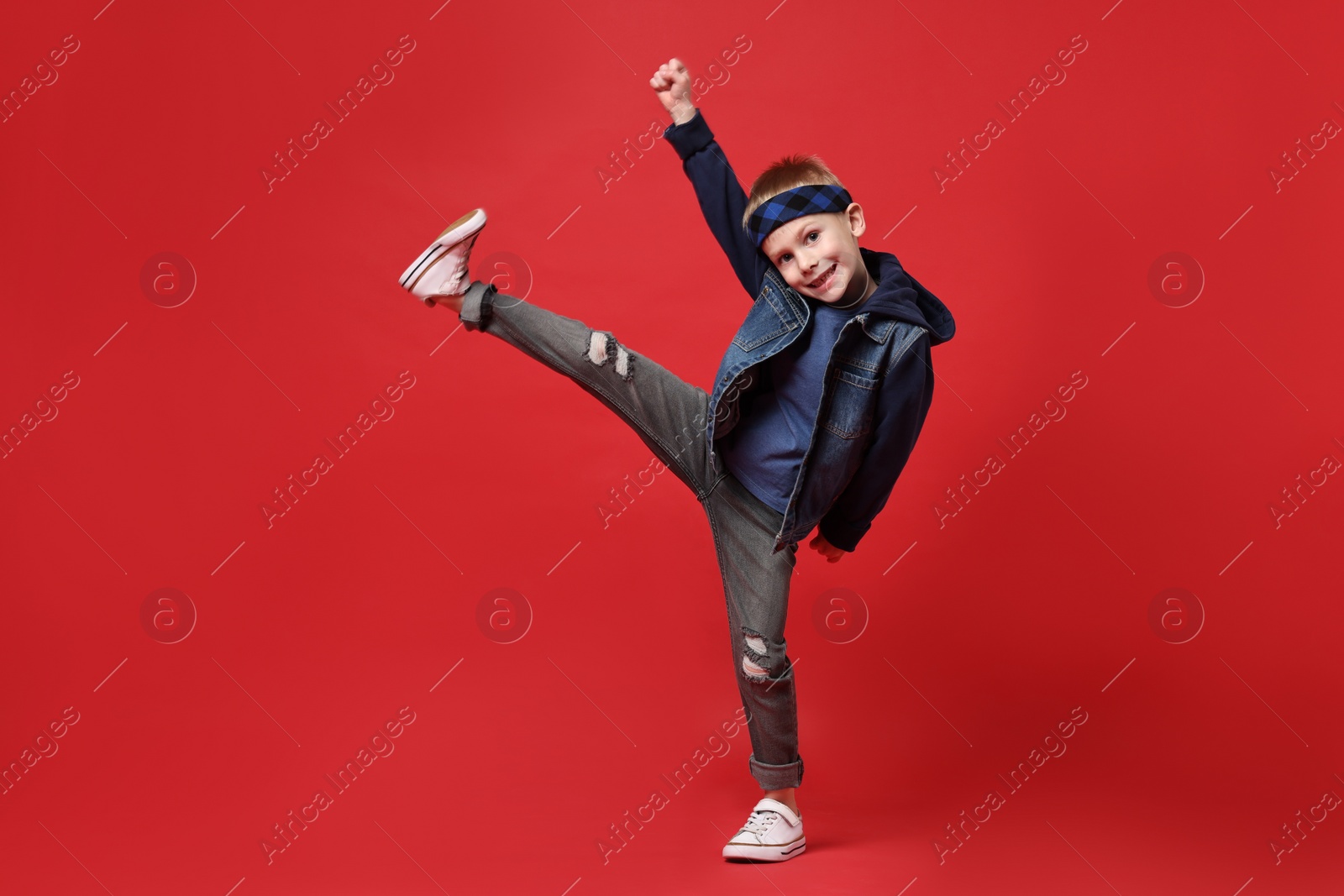 Photo of Happy little boy dancing on red background