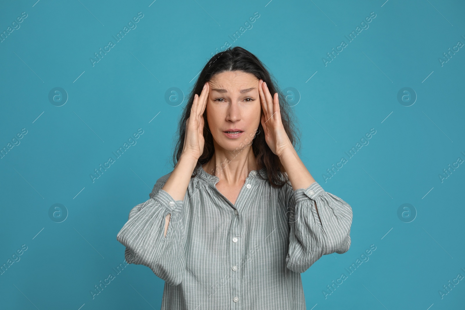 Photo of Mature woman suffering from headache on light blue background