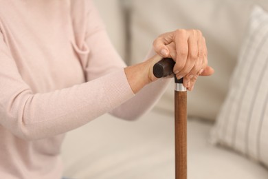Photo of Mature woman with walking cane on sofa, closeup