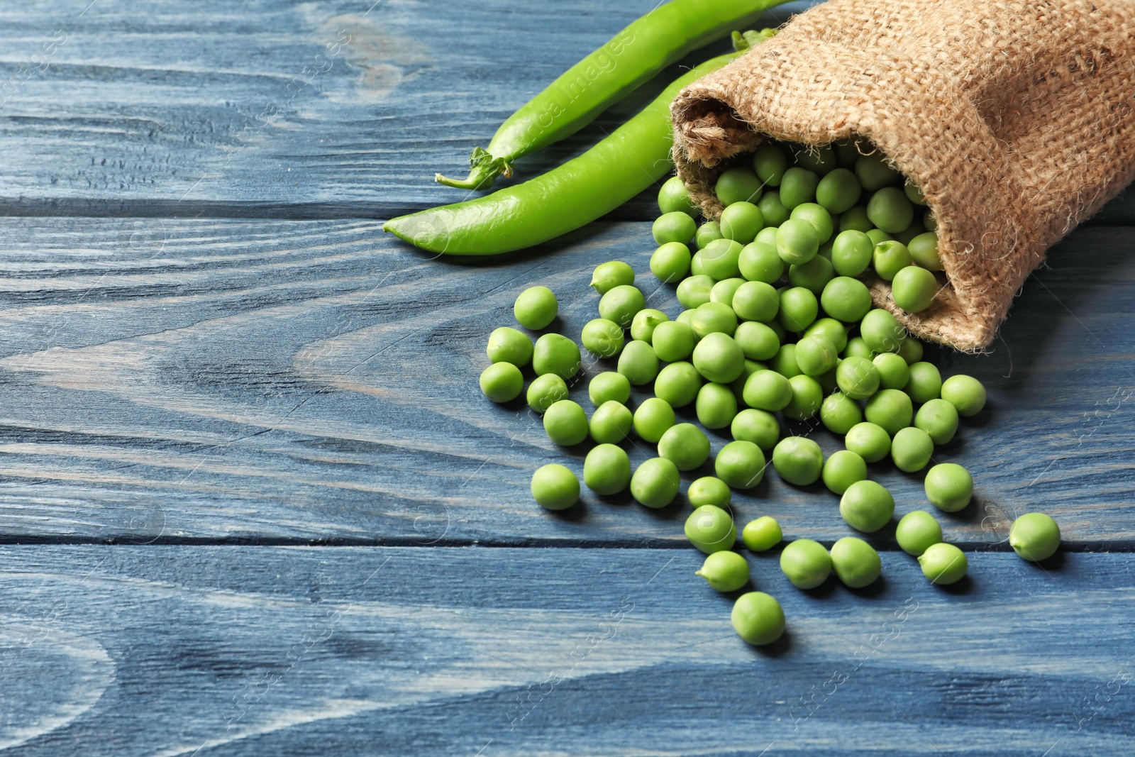 Photo of Sackcloth bag with fresh green peas on wooden background