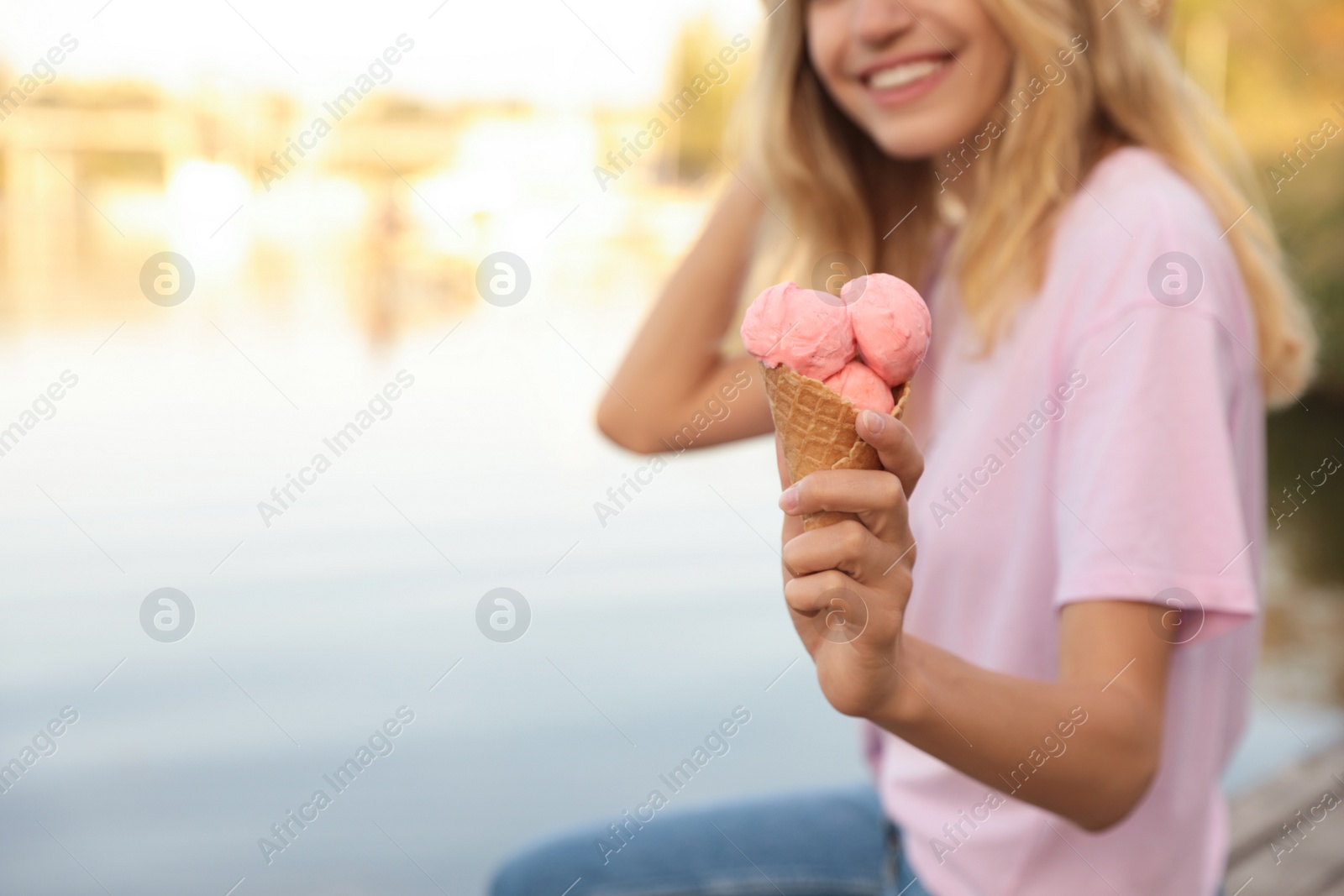 Photo of Happy young woman with delicious ice cream in waffle cone outdoors, closeup. Space for text