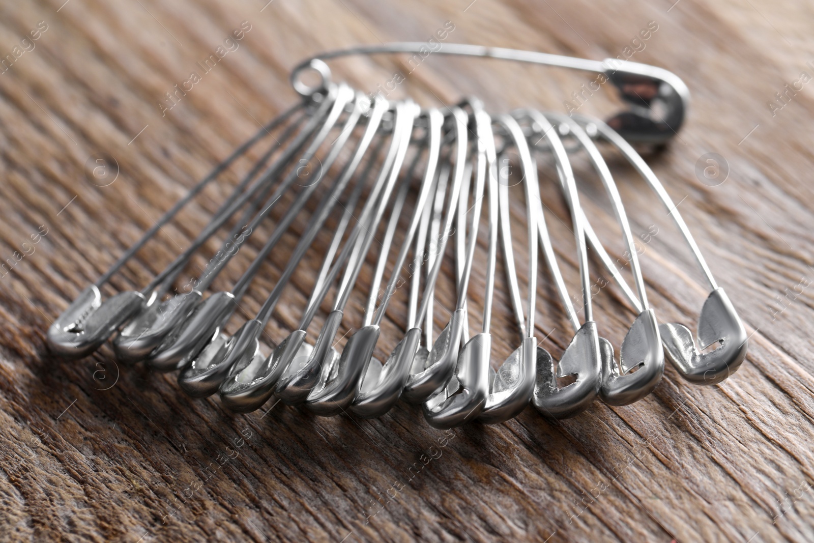 Photo of Many safety pins on wooden table, closeup