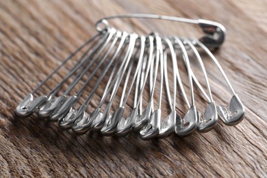 Many safety pins on wooden table, closeup