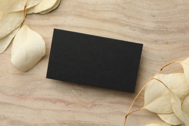 Photo of Blank business card and beige leaves on wooden table, flat lay. Mockup for design
