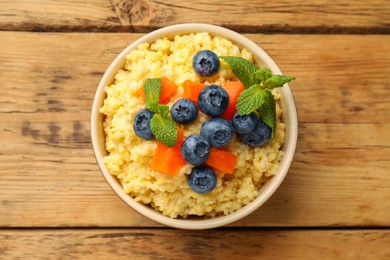 Photo of Tasty millet porridge with blueberries, pumpkin and mint in bowl on wooden table, top view