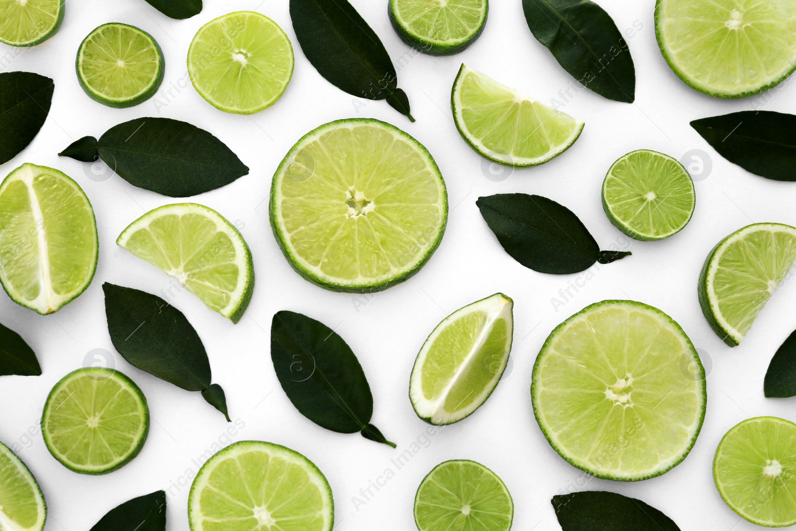 Photo of Fresh cut limes with leaves on white background, flat lay