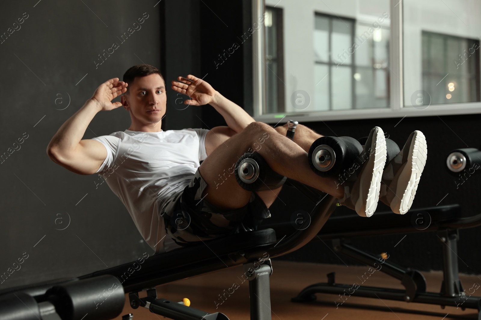 Photo of Man working out on adjustable sit up bench in modern gym