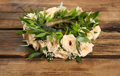 Photo of Wreath made of beautiful flowers on wooden table