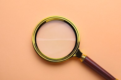 Magnifying glass on beige background, top view