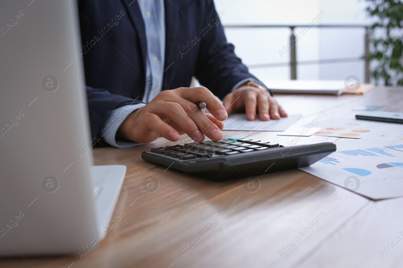 Photo of Tax accountant with calculator working at table in office, closeup