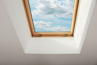 Photo of Skylight roof window on slanted ceiling in attic room, low angle view