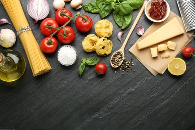 Different types of pasta, spices and products on dark textured table, flat lay. Space for text