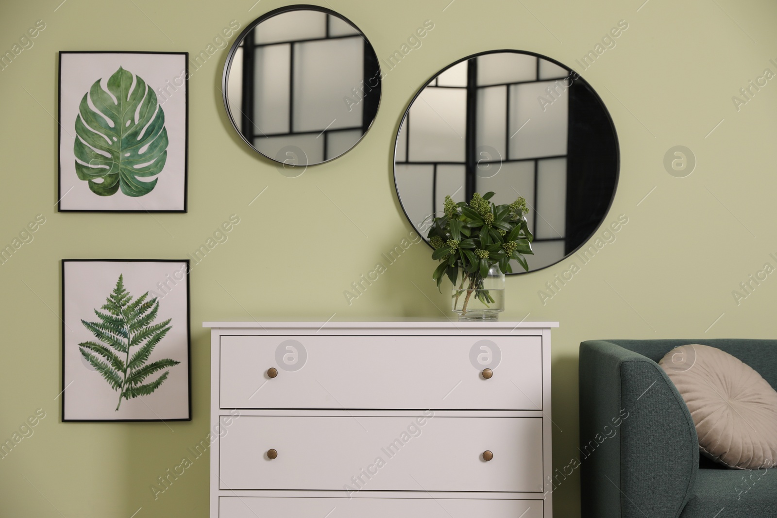 Photo of White chest of drawers with lamp and mirrors on wall in living room. Interior design