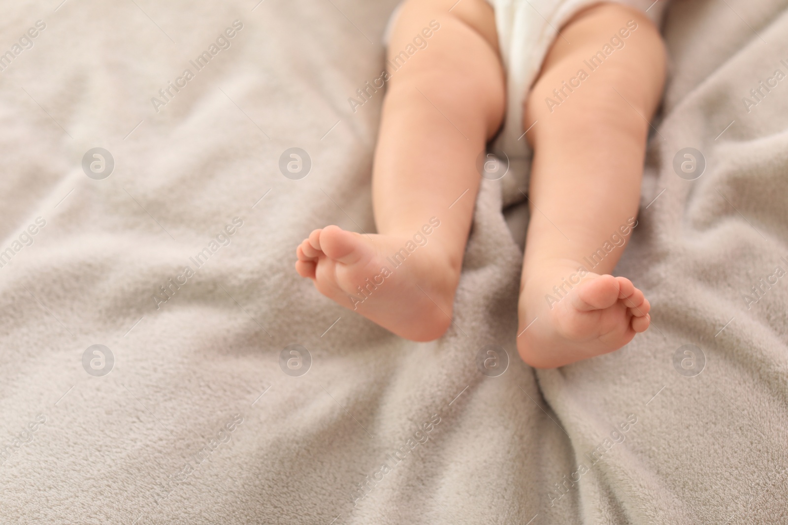 Photo of Cute little baby lying on bed, closeup of legs. Space for text