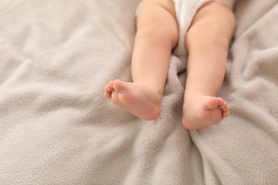 Photo of Cute little baby lying on bed, closeup of legs. Space for text