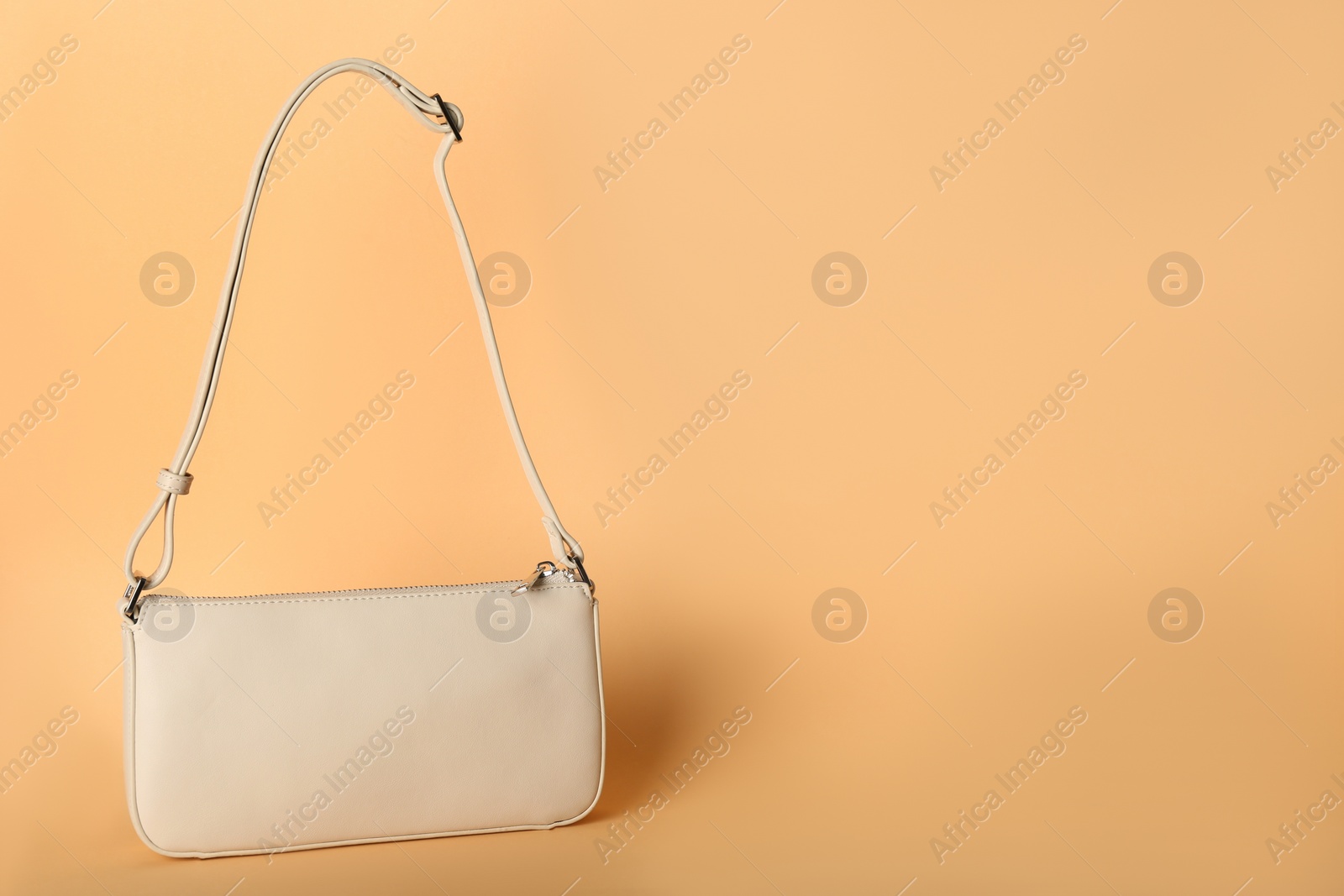 Photo of Stylish women's bag on pale orange background, space for text