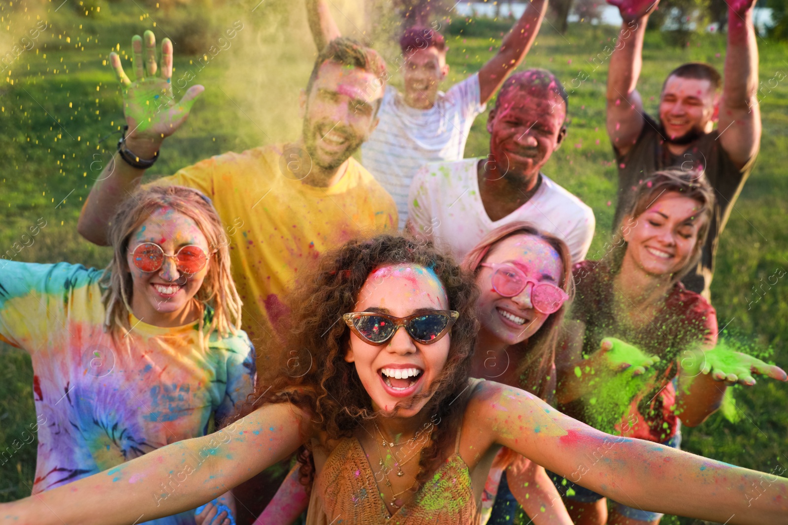 Photo of Happy friends covered with colorful powder dyes outdoors. Holi festival celebration