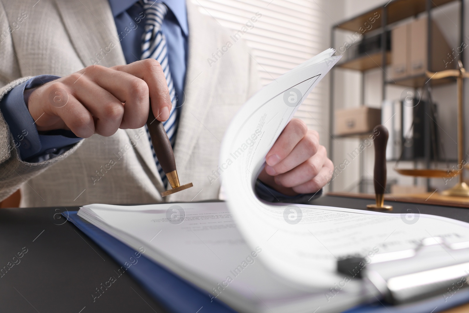 Photo of Notary stamping document at table in office, low angle view