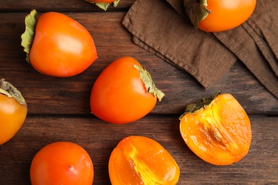 Photo of Delicious fresh persimmons on brown wooden table, flat lay