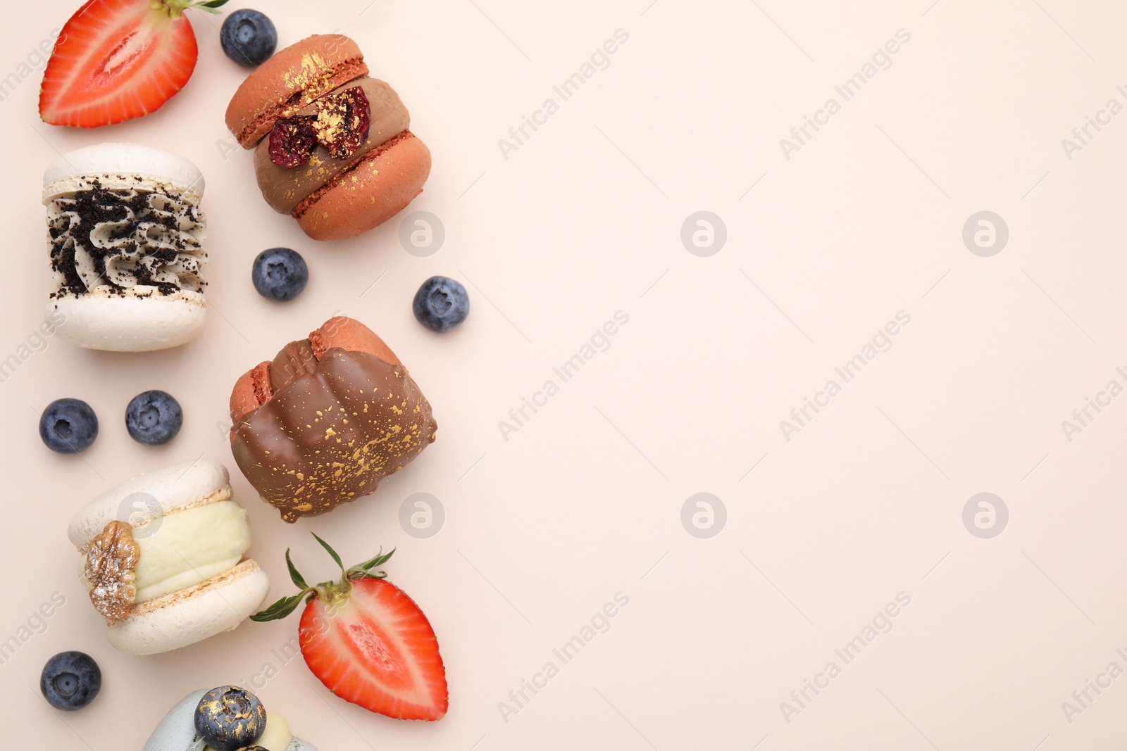 Photo of Delicious macarons and berries on beige table, flat lay. Space for text