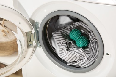 Green dryer balls and clothes in washing machine drum