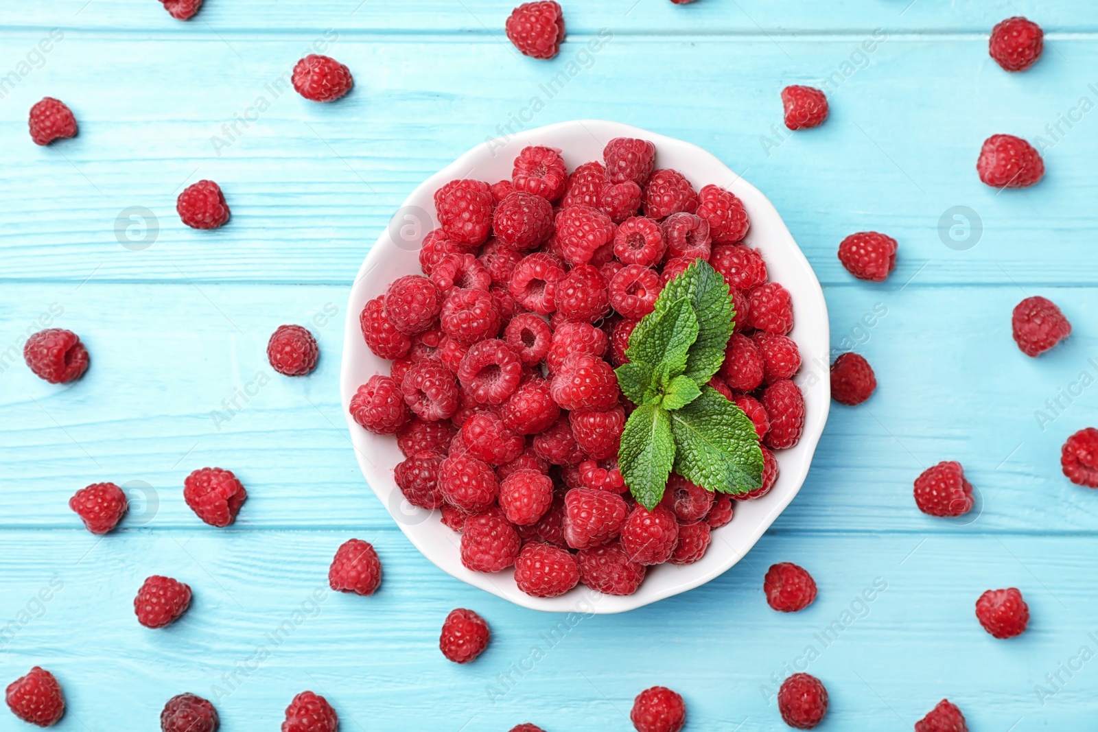 Photo of Plate with ripe aromatic raspberries on wooden table, top view