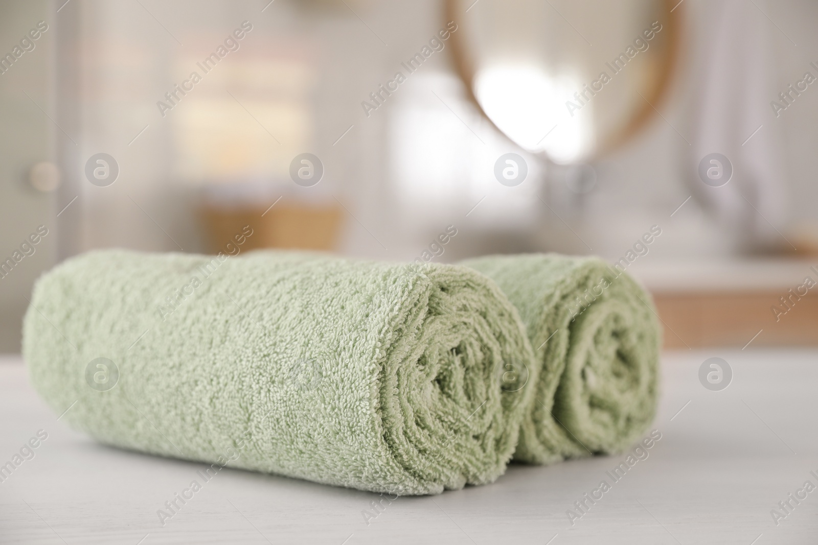 Photo of Clean rolled towels on white wooden table in bathroom