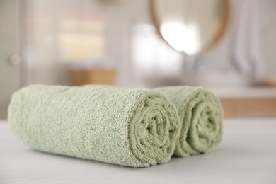 Photo of Clean rolled towels on white wooden table in bathroom