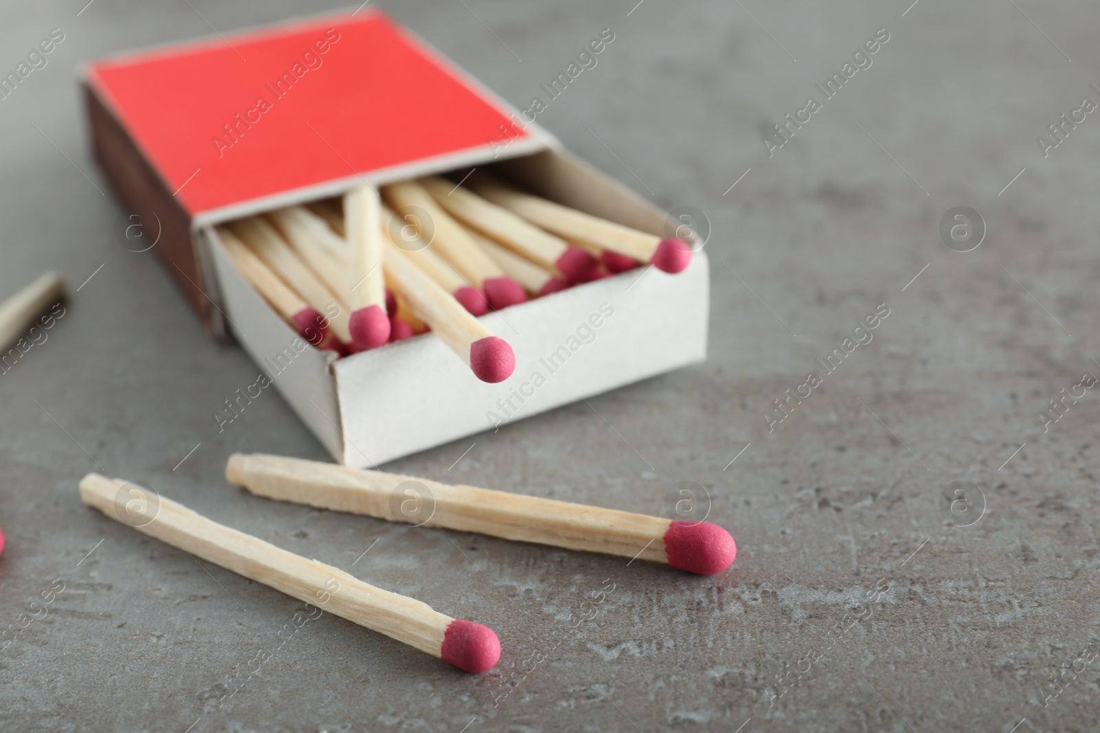 Photo of Open box and scattered matches on grey background, space for text