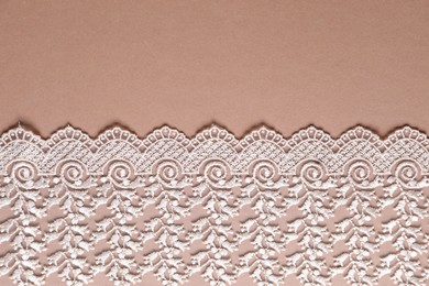 White lace on beige background, top view. Space for text