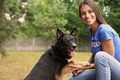 Photo of Female volunteer holding dog's paw at animal shelter outdoors