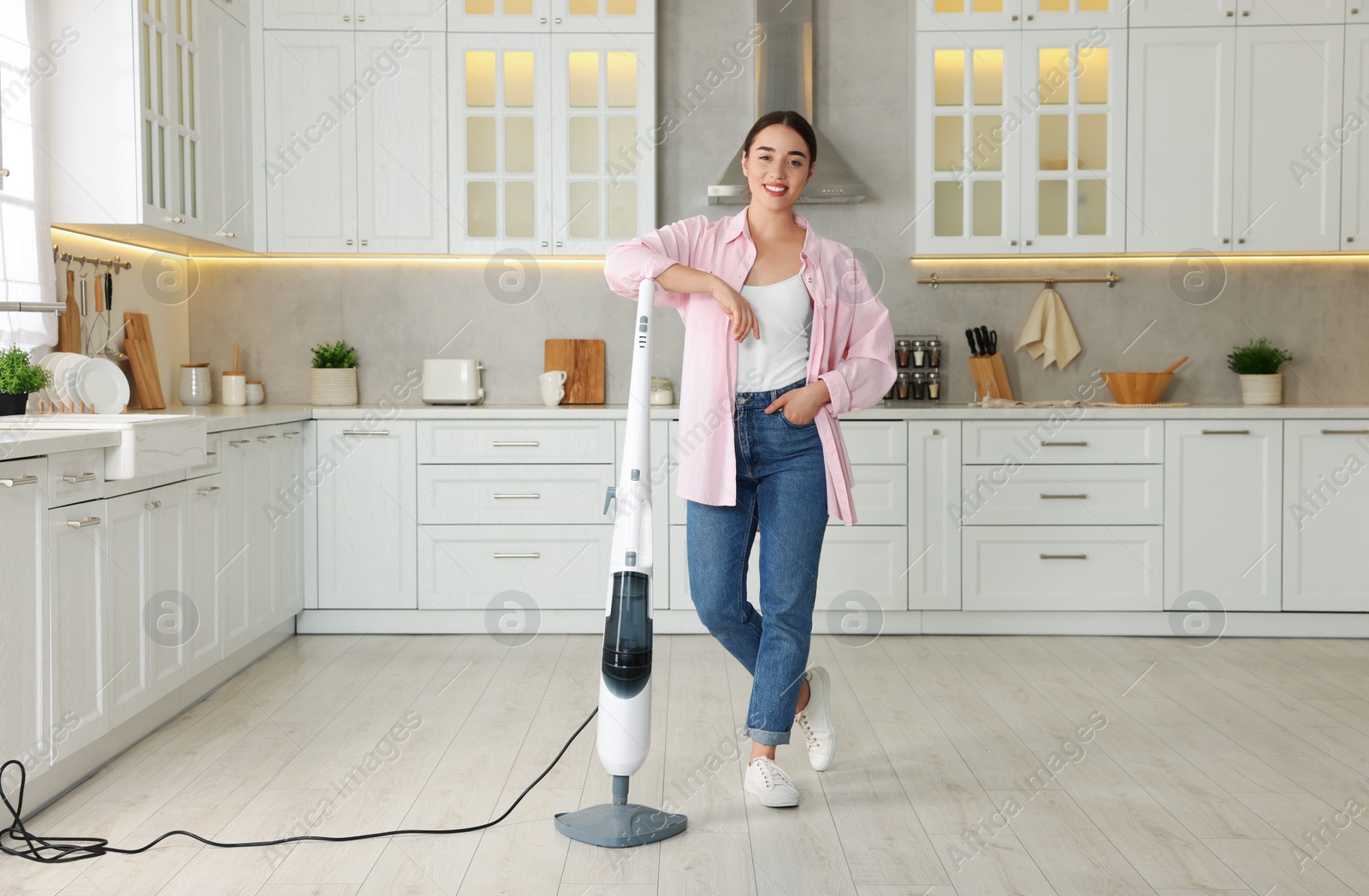 Photo of Happy woman with steam mop in kitchen at home