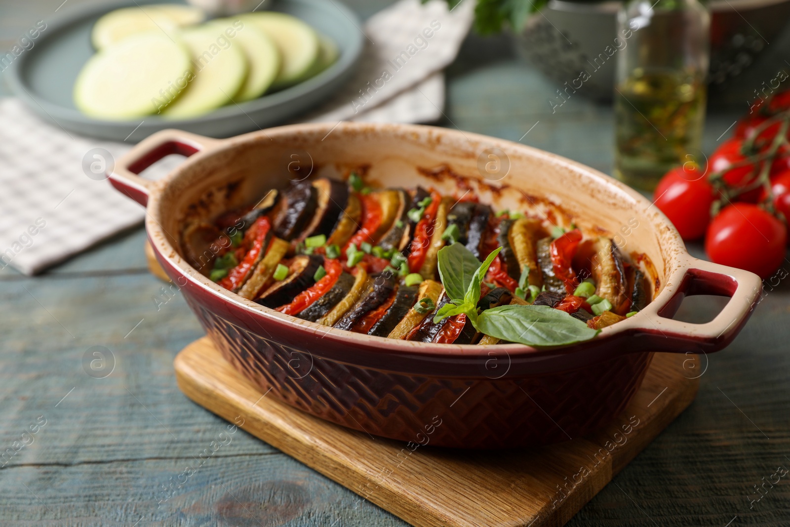 Photo of Delicious ratatouille in dish and ingredients on table