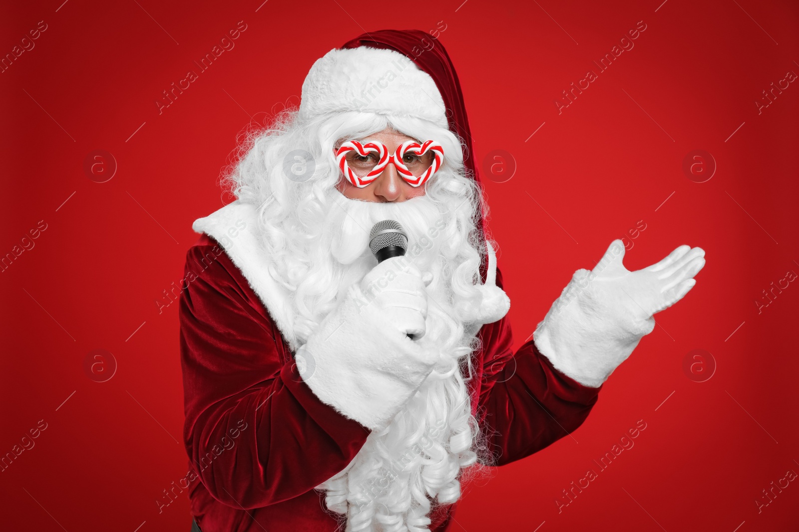 Photo of Santa Claus with microphone singing on red background. Christmas music