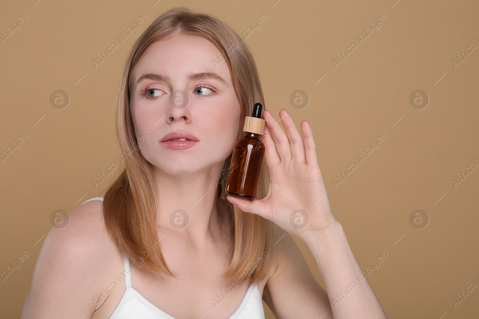 Photo of Beautiful young woman with essential oil on brown background. Space for text